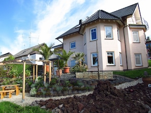 Blick auf Ferienwohnung und Garten mit Palmen und Sitzgelegenheit