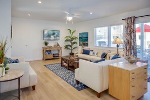 Vantage point from dining table and seating toward kitchen, living room and TV. Wood-look laminate flooring throughout.
                