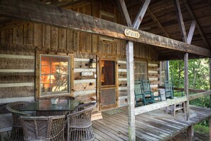 Front porch with rocking chairs, table, and views of the property