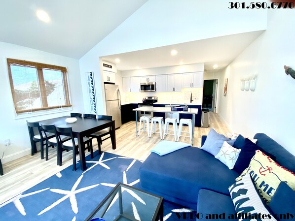 Living area with large sectional, flat panel HDTV, fireplace and 2 dining tables
