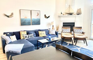 Living area with large sectional, flat panel HDTV, fireplace and 2 dining tables