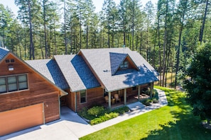 Front view of House and porch over looking the lush lawn and trees 