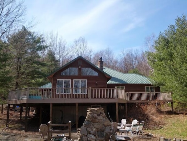 Front View, Large Deck, Patio Area with stone fire pit and charcoal grill.