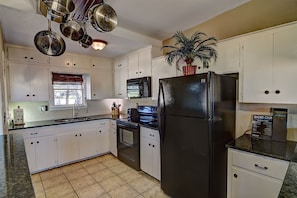 Large kitchen includes cooking essentials, service ware, coffee, microwave, oven