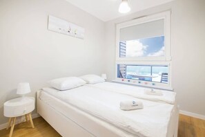 A cozy bedroom with a comfortable double bed, side tables, and large windows that brighten up the space. The minimalist design provides a calm and restful ambiance.