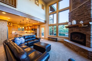 Living room with floor to ceiling windows, gas fireplace, open kitchen