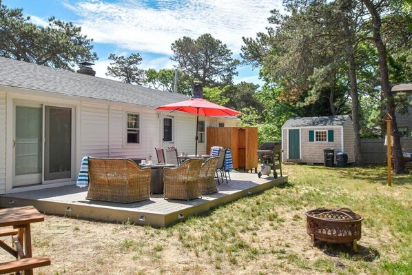 back deck with table chairs and umbrella and fire pit in backyard