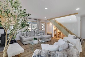 First floor living room with fireplace, smart TV, LED lighting, air conditioning, walkout onto wraparound deck and easy access to kitchen, bathroom and two bedrooms on the first floor.