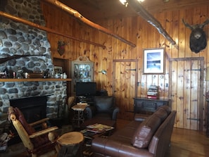 Sunlight streams in picture windows to the log cabin pine walls and tree beams