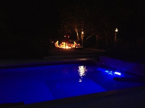 Night time: friends sitting around the fire pit overlooking the pool.
