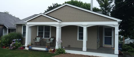 Front of house with porch and chairs for relaxing. Beautiful flowers in season.