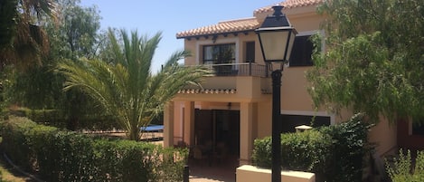 Rear of the villa with outdoor dining furniture and gate leading to the pool