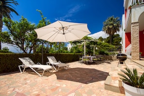 Outdoor dining area with a barbeque in front of the living room and kitchen