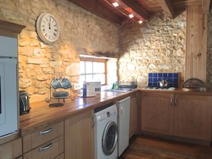 Kitchen area with washing machine, fridge and cooker.