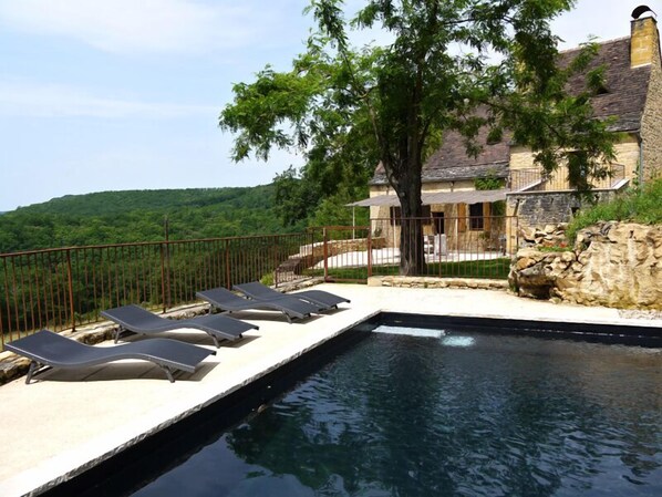 Heated swimming pool, terrace and house in the back
