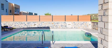 Private swimming pool area with sun beds and umbrellas