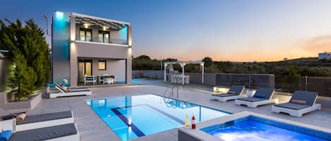 The pool terrace and building are beautifully lit at night.