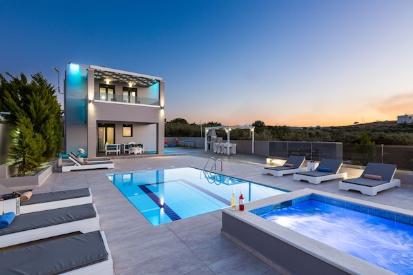 The pool terrace and building are beautifully lit at night.