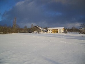 Blick auf das Haus über die verschneite Wiese