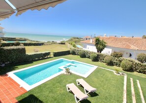 Meerblick und Sicht auf Pool und Garten von Terrasse.