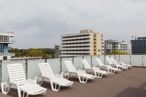 A spacious rooftop terrace with several sun loungers, offering an ideal spot for relaxation and city views.