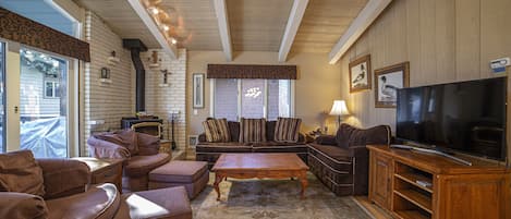 Expansive living area with flat screen television and woodburning fireplace