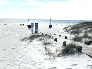 Sugar white sands beach entry point with trash cans and a boardwalk.
