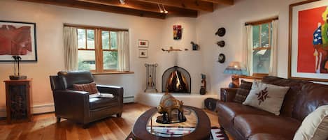 Our art-filled living room with Navajo rug, kiva fireplace and leather seating