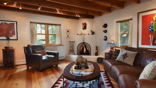 Our art-filled living room with Navajo rug, kiva fireplace and leather seating