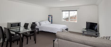 Room view with queen bed, table, tv, sleeper sofa, skylight