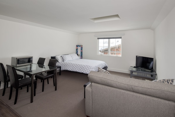 Room view with queen bed, table, tv, sleeper sofa, skylight