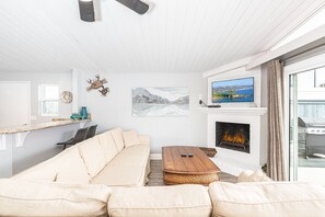 The living area includes sofa, cable TV,  dining table with seating for 6, and kitchen beyond.
                