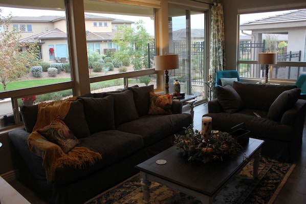 Living room area with view to green walking area. Large comfy couches. 