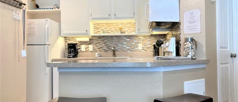 Updated kitchen with glass backsplash and under cabinet lighting.