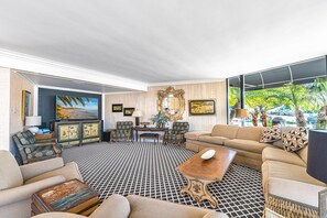 Pictured here is the main living area, with large sectional, additional seating, back-to-back gas fireplace, TV and sound system, and sliding doors out to the front patio.
                