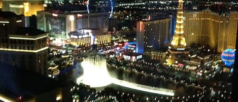 Night view of the Bellagio fountains, the High Roller and the Eiffel Tower.