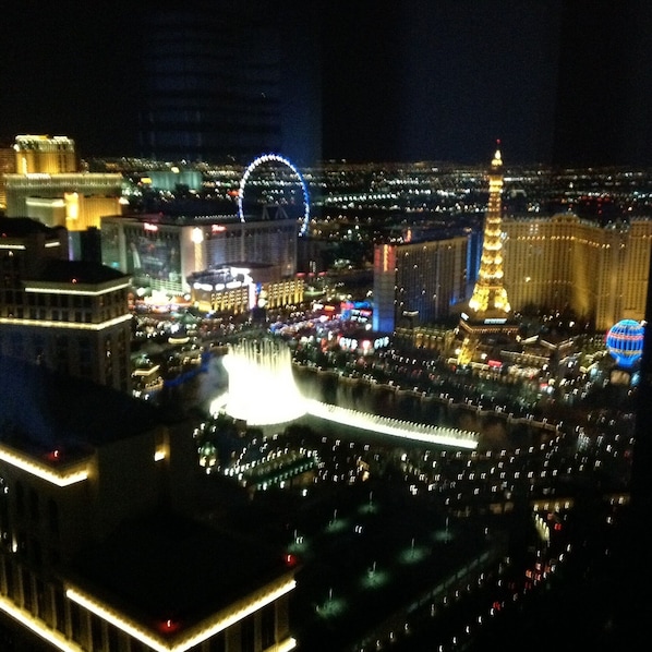 Night view of the Bellagio fountains, the High Roller and the Eiffel Tower.