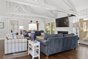 Great room at the top of the stairs with ample seating, large TV, beautiful beams, doors leading out to the screened in porch, and door leading to the master bedroom