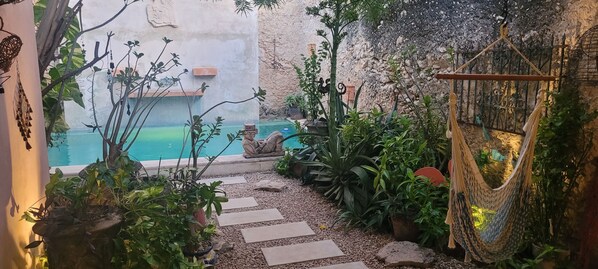 View of the pool from the covered patio area.  Chaac Mool, hammock chair.