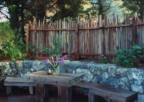 Local rock wall and built in wooden table & bench on the cottage stone patio 