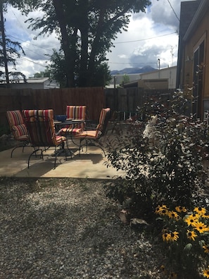 Backyard patio with gas grill, seating with comfy cushions and wildflower garden