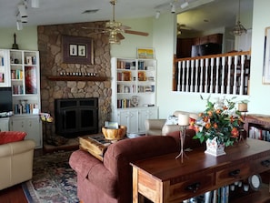 Living room with stone fireplace, TV, and a view of the lake