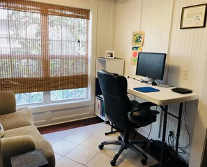 Work/office area in well-lit sunroom.  Monitor has a blue VGA (15 pin) connector