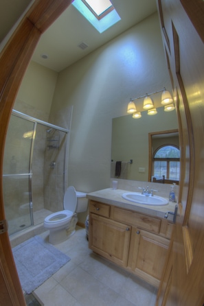 Upstairs bedroom bathroom with large shower, vaulted ceiling, and skylight.
