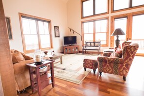 Living room area with couch, TV and chairs. 
