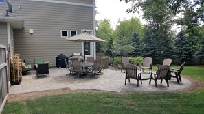 New Paver Patio with Firepit, Dining Table, Couch and a Weber charcoal grill.