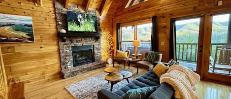 Living room with beautiful stone fireplace, vaulted, beam ceiling, and views!