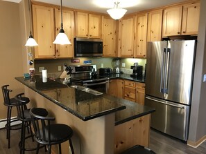 Kitchen with granite counters, stainless steel appliances and coffee station