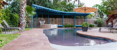 Beach entry pool with hot tub, plenty of seating with shade.