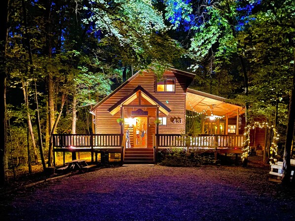 Bathed In The Glow Of Soft Amber Lights, The Cabin Warmly Welcomes You At Night